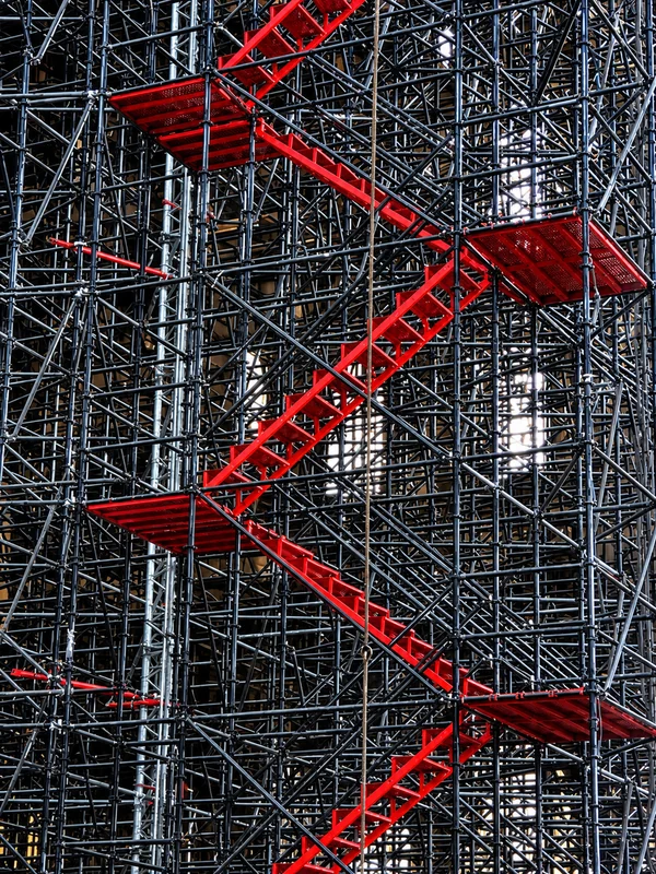 Struktur scaffolding berwarna merah-oranye dengan tangga di sebuah bangunan