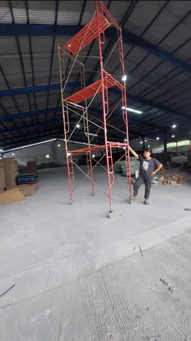 Menara scaffolding berdiri di dalam gudang beratap rangka baja